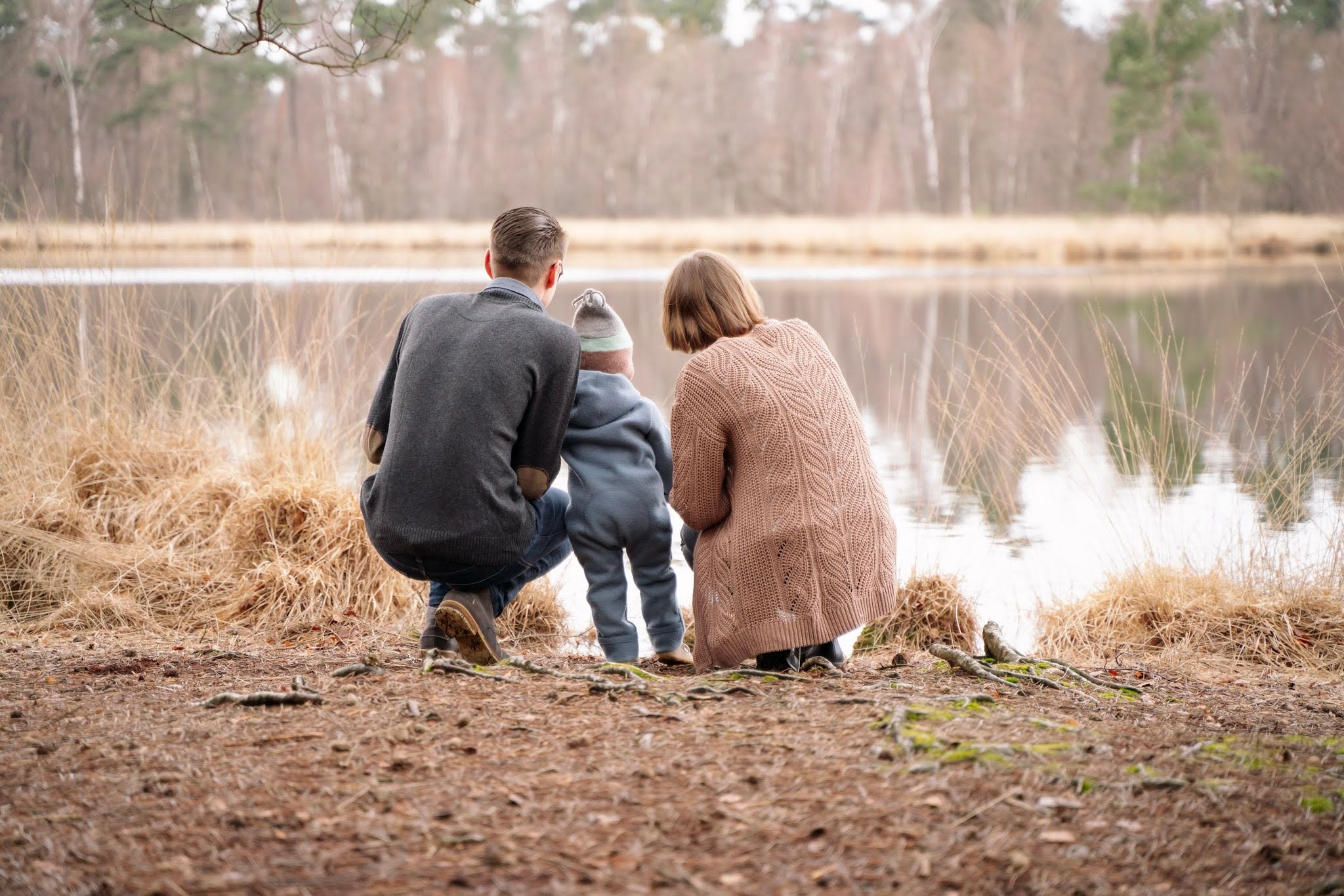 Eltern knien am See mit ihrem kleinen Sohn