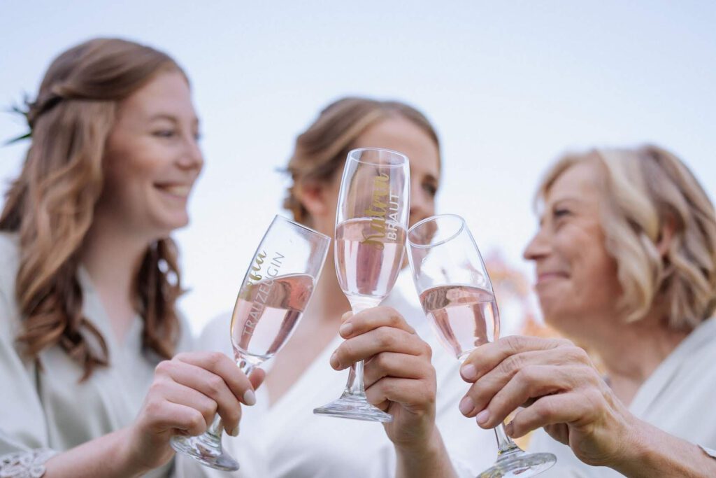 Brautmutter, Braut und Trauzeugin stoßen mit Sekt an