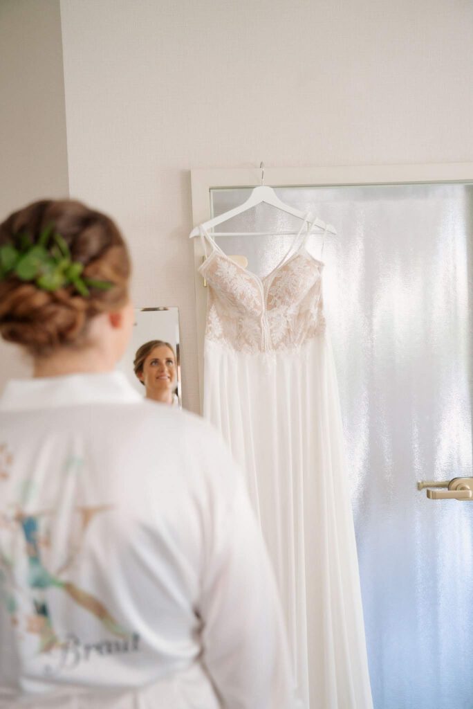 Braut bestaunt ihr Kleid auf dem Bügel